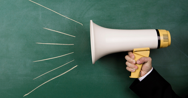 Person holding megaphone against a chalkboard